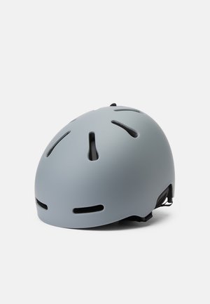 Elmetto grigio con finitura opaca, forma arrotondata, diverse fessure di ventilazione e cinturini regolabili. Progettato per la sicurezza e il comfort.