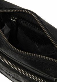 Intérieur d'un portefeuille en cuir noir avec un compartiment zippé, surface texturée et quincaillerie en argent ; comprend plusieurs emplacements pour cartes et doublure foncée.