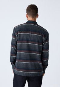 Camicia con bottoni realizzata in tessuto a righe nei colori blu navy, grigio e bordeaux; presenta un colletto e polsini con bottoni.