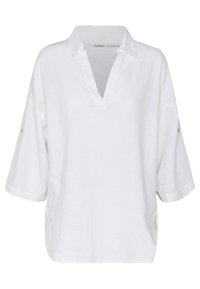 Blusa bianca in lino con scollatura a V, maniche corte con dettaglio a bottone e spacchi laterali per facilitare i movimenti. Tessuto testurizzato.