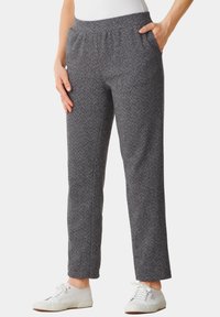 Grijze herringbone-patroon broek met een elastische tailleband en zijzakken, gecombineerd met witte sneakers. De stof heeft een zachte textuur.