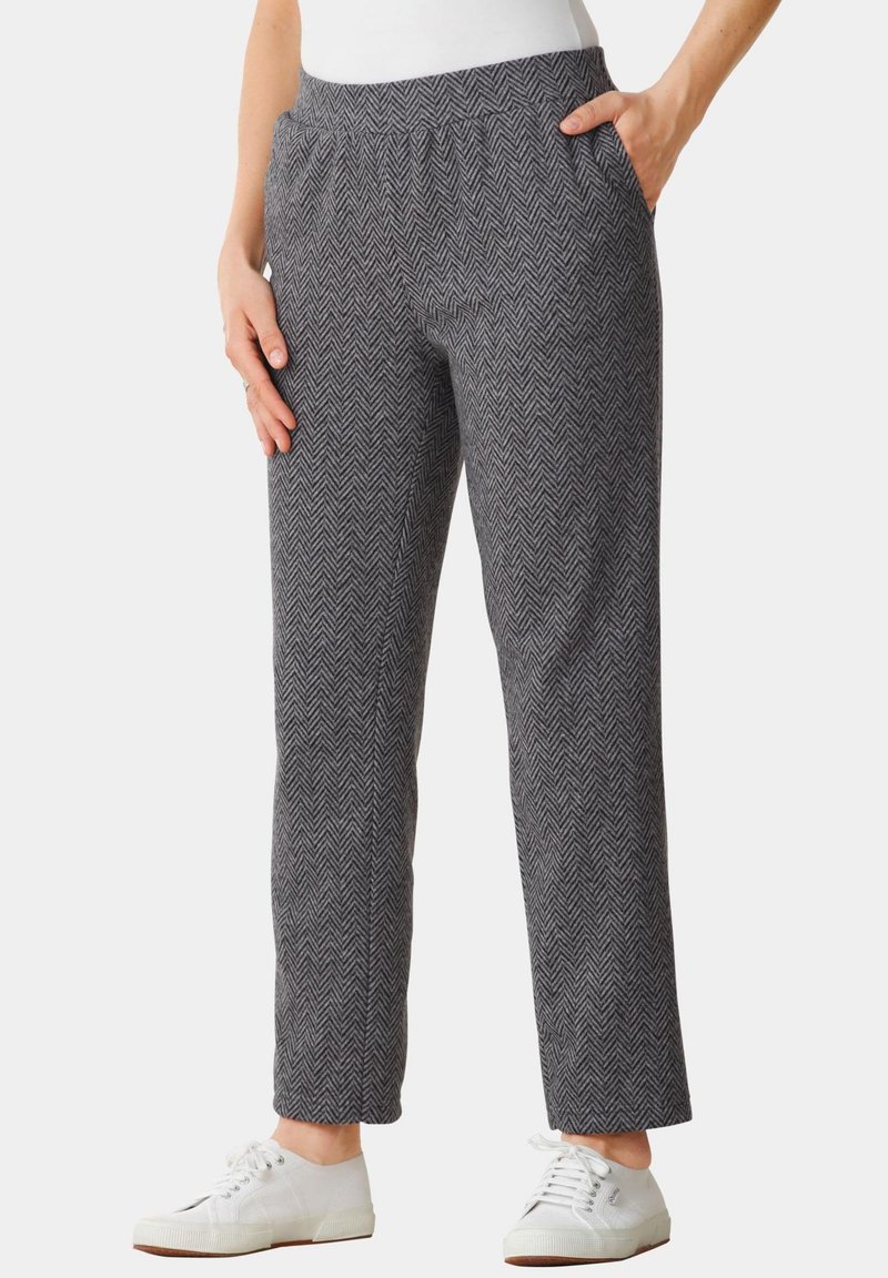Grijze herringbone-patroon broek met een elastische tailleband en zijzakken, gecombineerd met witte sneakers. De stof heeft een zachte textuur.