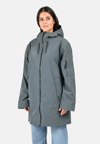 Parka imperméable grise avec un col haut, une fermeture éclair frontale, deux poches latérales et des cordons de serrage réglables à la capuche. Tissu doux et texturé.