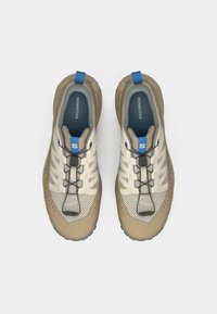 Αθλητικά παπούτσια σε ανοιχτό μπεζ χρώμα με πλέγμα στο επάνω μέρος, καφέ λαστιχένια σόλα, μπλε λεπτομέρειες και σύστημα δέσιμου με κορδόνια. Διακριτή υφή με σχέδιο στις πλευρές.