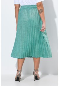 Gonna midi pieghettata in tessuto teal texturizzato, con una cintura larga e un leggero luccichio. Abbinata a sandali con tacco alto metallici.