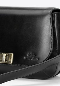 Bolso de cuero negro con forma estructurada, clasp de hardware de latón brillante, logo en relieve y correa de cuero ajustable.