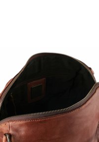 Bolso de cuero marrón con apertura con cremallera, que presenta un forro interior oscuro y un bolsillo plano en su interior. Textura suave con un hardware minimalista.