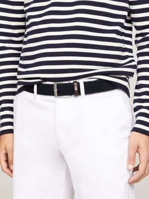 Black woven belt with a silver metal buckle, worn over white pants, paired with a navy and white striped long-sleeve shirt.