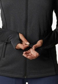 Giacca nera con zip, maniche lunghe, fori per pollice e tessuto testurizzato. Presenta una vestibilità aderente e cuciture a contrasto ai polsini e all'orlo.