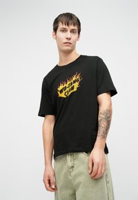 Μαύρο βαμβακερό T-shirt με ένα πολύχρωμο λογότυπο "Wu-Tang Clan" σε φλόγες. Κοντά μανίκια και άνετη εφαρμογή με στρογγυλή λαιμόκοψη.