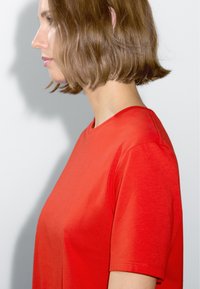 T-shirt rosso a maniche corte con scollo rotondo, realizzato in tessuto leggero e morbido, con una vestibilità rilassata e dettagli di cucitura minimi.