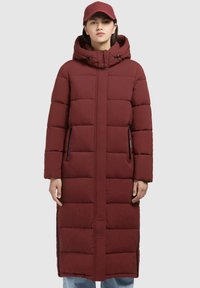 Bordo puffer kaput s kapuljačom, dužine do koljena, s šupljikavim dizajnom, bočnim zip džepovima, a upareno s odgovarajućom kapom. Mekani materijal, ležeran kroj.