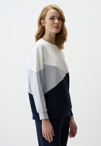 Kleurgebloqueerde sweatshirts met een ronde hals in wit, lichtgrijs en marineblauw. Gemaakt van zacht, glad materiaal met ribgebreide mouwen en onderrand.