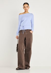 Pull bleu clair à épaules dénudées avec une taille à cordon, associé à un pantalon ample marron à jambes larges et des bottes marron ; design minimaliste.