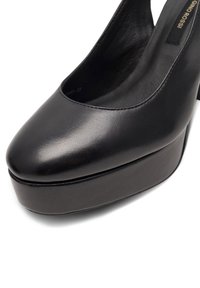 Czarne skórzane buty na wysokim obcasie z zaokrąglonym noskiem, platformą i błyszczącym wykończeniem. Posiadają design typu slingback oraz minimalne detale szycia.