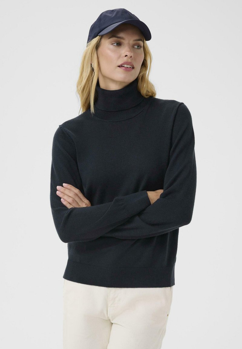 Black turtleneck sweater in a soft knit fabric with long sleeves, paired with a dark baseball cap. The fit is relaxed with ribbed accents.