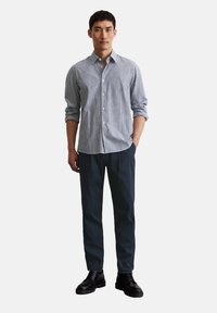 Striped button-up shirt in light blue and white, paired with dark pants and black shoes. The shirt has long sleeves and a classic collar.