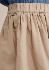 Homokszínű szövet szoknya, melynek derékrészén ráncolt pliszők találhatók, rugalmas derékpánttal és egy kis fémbetéttel.