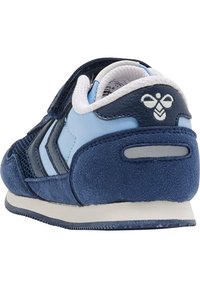 Blå och marinblå syntetiska sneakers med en mocka-liknande yta, utrustade med mesh-detaler, en vadderad krage och tre dekorativa ränder på sidan.