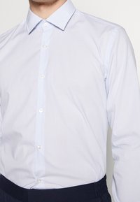 Lichtblauw gestreept overhemd met knopen, een puntige kraag en lange mouwen. Bevat witte knopen en heeft een gladde, geweven textuur.