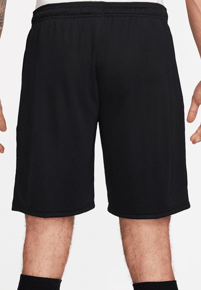 Shorts de sport noirs jusqu'aux genoux portés par une personne, vus de dos avec une ceinture élastique visible et des jambes nues.