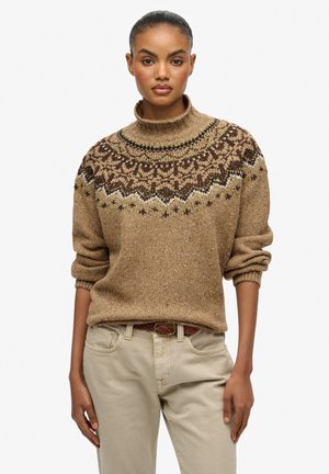 Suéter de punto marrón con cuello alto y una joroba con un patrón en tonos más oscuros, combinado con pantalones beige. El suéter tiene mangas arremangadas y un acabado texturizado.