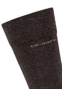 Brun strikket sok med en tekstureret overflade og en glat manchet, der har et diskret beige logo langs siden.