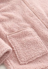 Fleece jack in zachte roze met textuur en pluche stof. Beschikt over een zachte kraag, ritssluiting en een opgestikte zak aan de voorkant.