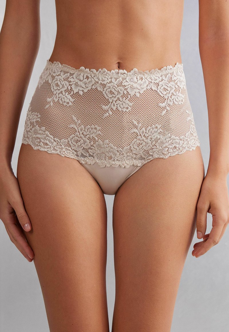 Las panties de encaje beige de cintura alta presentan patrones florales, bordes ondulados y una capa interior suave. El diseño combina transparencia y cobertura.