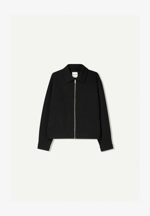 Zwarte zip-up jack met een brede kraag, voorzien van twee grote voorzakken en een gladde textuur. Ontworpen met een relaxte pasvorm en lange mouwen.