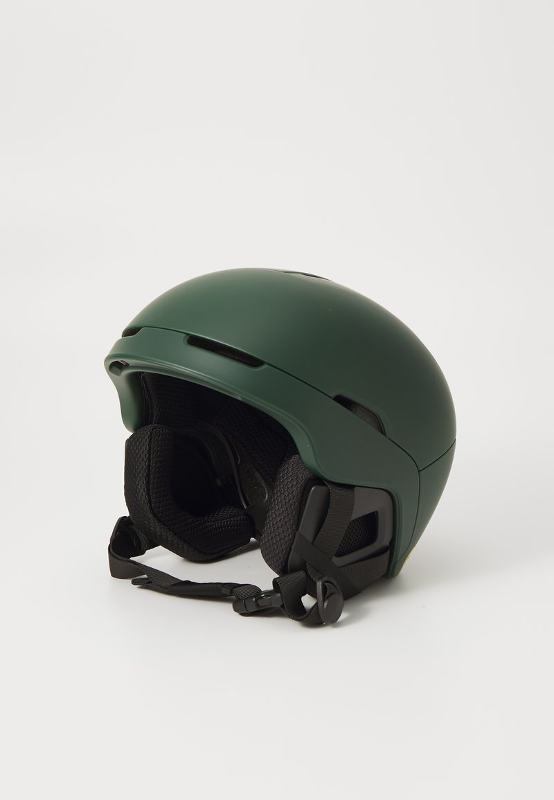 Grüner Helm mit einer glatten, matten Oberfläche. Verfügt über Belüftungsöffnungen, schwarze Polsterung und verstellbare Riemen für einen sicheren Sitz.