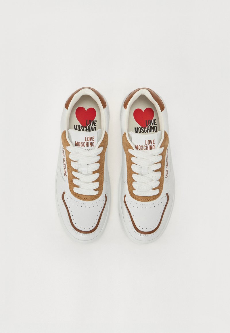 Sneakers bianche con dettagli in suede marrone chiaro, punta rotonda, dettagli perforati e chiusura con lacci. Logo stampato e design a forma di cuore sulla soletta.
