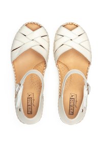 Sandales en cuir blanc avec des brides croisées, bout ouvert et bride de cheville. Semelle intérieure en cuir naturel avec perforations. Bords tressés.