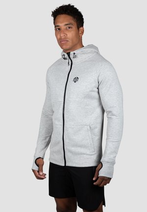 Ljusgrå zip-up hoodie i mjukt material, med en svart dragkedja, en liten logotyp på bröstet och tumhål i ärmarna.