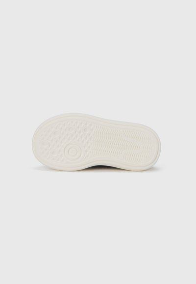 Λευκό ελαστικό πέλμα αθλητικού παπουτσιού με υφή, κυκλικά και οβάλ εγκοπές, και ελαφριά καμπύλη στη φτέρνα. Λείο και ανθεκτικό φινίρισμα.