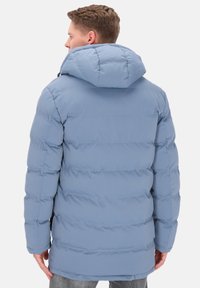 Jasnoniebieska pikowana kurtka z kapturem, z przeszyciami, mankietami z otworami na kciuki i zapięciem na zamek, odpowiednia na zimną pogodę.