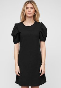 Robe noire à manches courtes avec des manches volumineuses, col rond et coupe décontractée. Fabriquée dans un tissu lisse au design minimaliste.