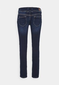 Mörkblå slim-fit jeans sedd bakifrån med två bakfickor och detaljerad sömnad på midjebandet och fickorna.
