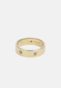 Anillo de metal en tono dorado con una banda lisa y diseños de explosión estelar, con pequeños cristales incrustados, tamaño 8, grabado con "FOSSIL."
