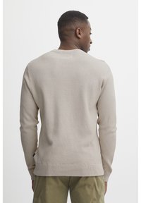 Ljus beige strukturerad stickad tröja med rund hals och långa ärmar. Har ribbade cuffar och nederkant, vilket ger en modern passform.