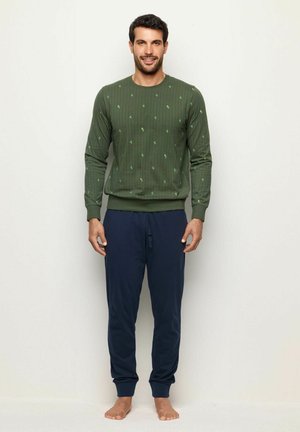 Grünes Langarmhemd mit vertikalen Streifen und kleinen Blattmustern, kombiniert mit navyblauem Jogginghose mit elastischem Bund.
