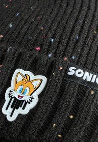 Musternit räpane, millel on tekstuurne ribakujundus ja mitmevärvilised täpid. Omab valget joonistuskaru embleemi ja "SONIC" sildi.