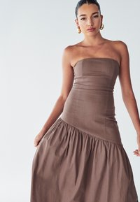 Strapless, braunes Kleid aus Stoff mit einem taillierten Oberteil und einem fließenden, gerafften Rock. Glatte Textur mit einem gestuften Design.