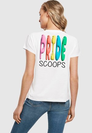Valkoinen puuvillapaita, jonka takana on suurta, värikylläistä tekstiä, jossa lukee "PRIDE SCOOPS" vaaleanpunaisella, keltaisella, sinisellä ja vihreällä, kiiltävällä tippavaikutuksella.