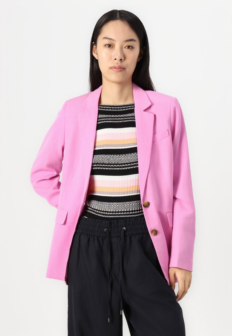 Heller pinker Blazer mit taillierter Passform, ausgestattet mit zwei vorderen Taschen und zwei braunen Knöpfen. Getragen über einem mehrfarbig gestreiften Oberteil in Schwarz und Pastellfarben.