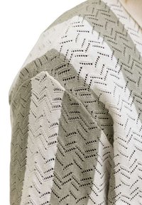 Πλεκτό ύφασμα με εναλλασσόμενες φαρδιές ρίγες σε μπεζ και εκρού, με ζιγκ-ζαγκ δαντελωτό σχέδιο.