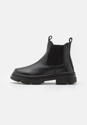 Botas Chelsea de cuero negro con paneles elásticos acanalados a los lados, puntera redondeada y suela gruesa. Incluyen tiradores para facilitar su uso.