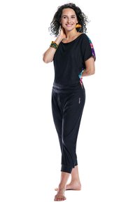 Black semi-fitted top with colorful patterned sleeves paired with black cropped pants, featuring a relaxed design and gathered cuffs.