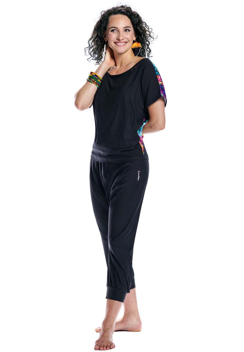 Black semi-fitted top with colorful patterned sleeves paired with black cropped pants, featuring a relaxed design and gathered cuffs.