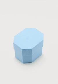 Φωτεινό γαλάζιο οκταγωνικό κουτί κοσμημάτων με υφή και διακριτικό ανάγλυφο σχέδιο στο καπάκι, πάνω σε απλό φόντο.